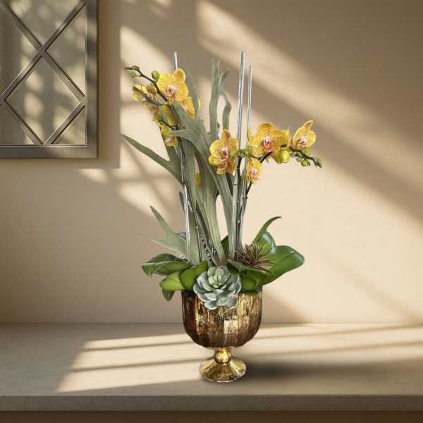Yellow orchids in a gold pedestal vase with succulents