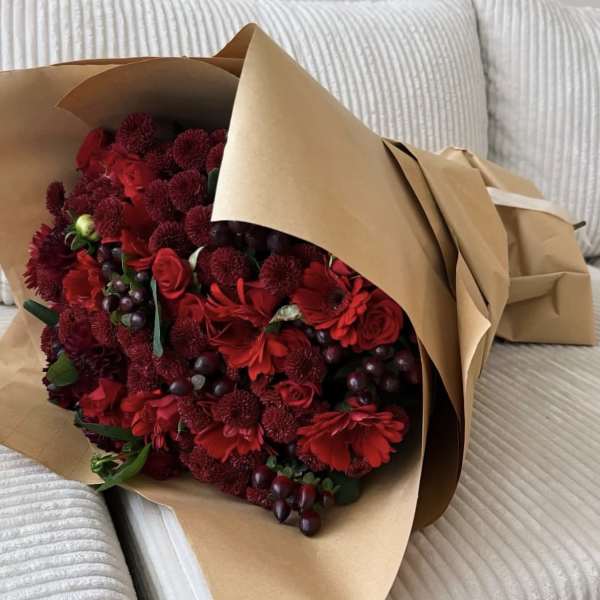 Bouquet of red flowers wrapped in brown paper