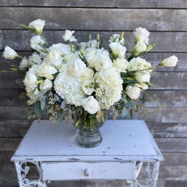 White floral arrangement in a clear glass vase on a small table