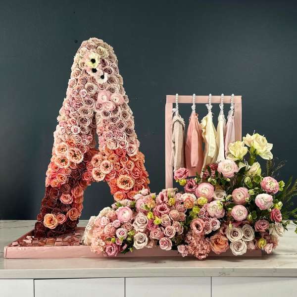 Pink rose floral display with a hanging rack of pastel clothes and a bouquet arrangement