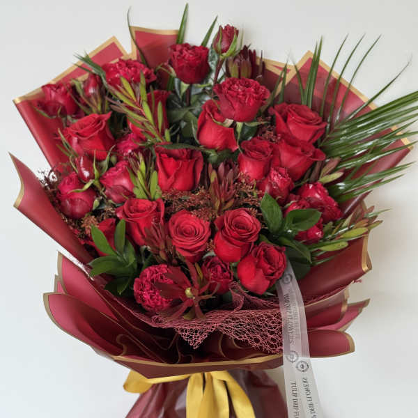 Bouquet of red roses and carnations wrapped in burgundy paper
