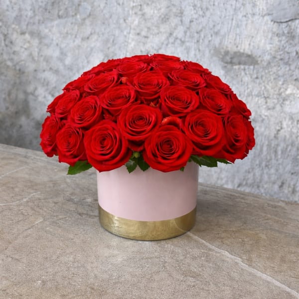 Round bouquet of red roses in a pink and gold box