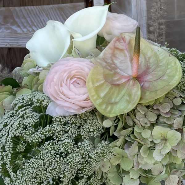 Bouquet with white calla lilies, pale pink ranunculus, and an anthurium bloom