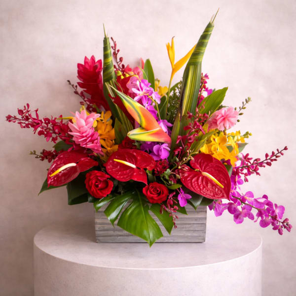 Tropical flower arrangement with red anthuriums and orchids in a gray wooden box