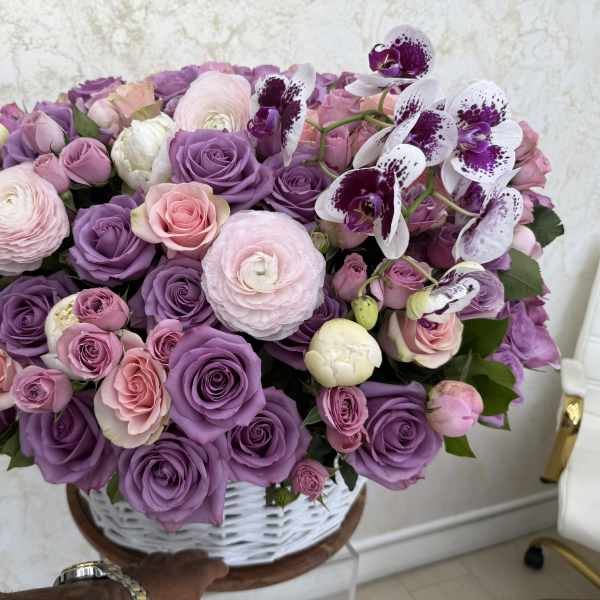 Large bouquet of pink and purple roses with spotted orchids in a white basket