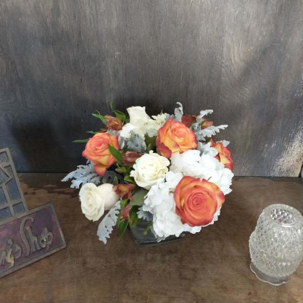 Bouquet of orange and white roses with white hydrangeas in a vase
