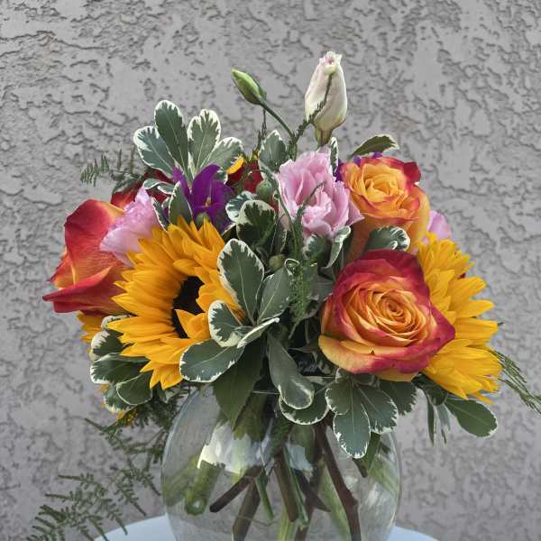 Sunflowers and roses arranged in a glass vase