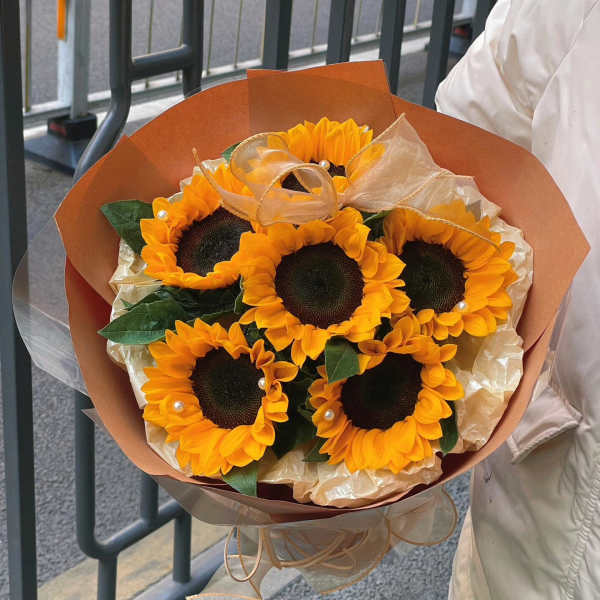 Bouquet of sunflowers wrapped in brown paper with a ribbon