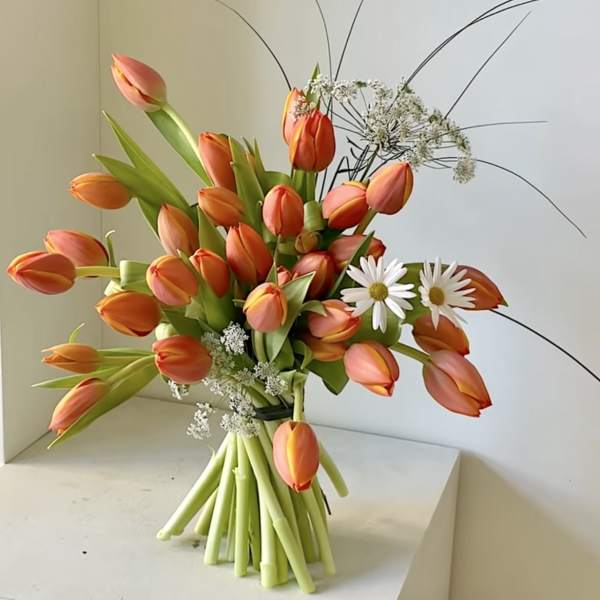 Bouquet of orange tulips with white daisies and airy filler