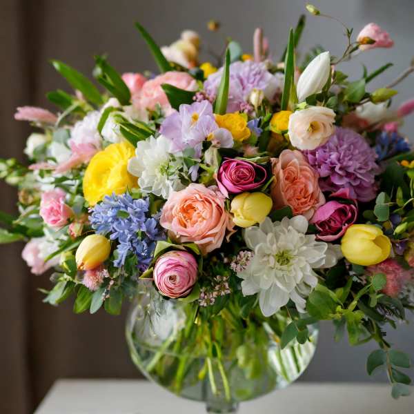 Mixed pastel flower arrangement in a glass pedestal vase