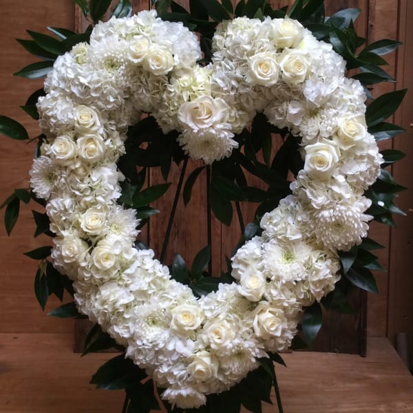 White floral heart wreath with roses and chrysanthemums on a wooden backdrop