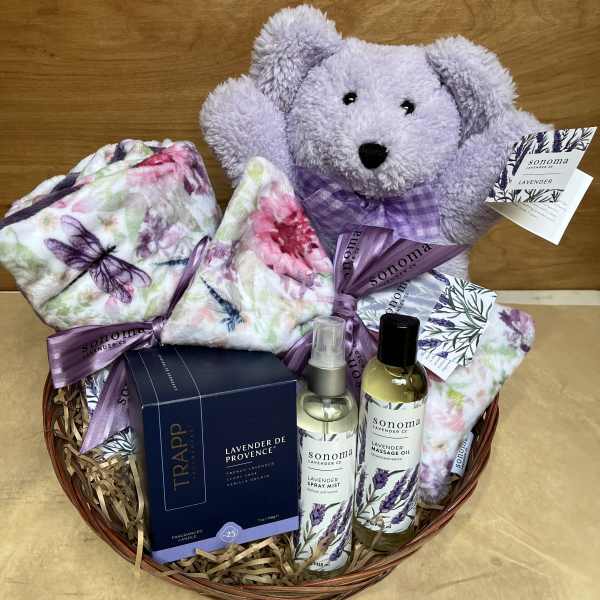 Lavender gift basket with a teddy bear, blankets, and bath products