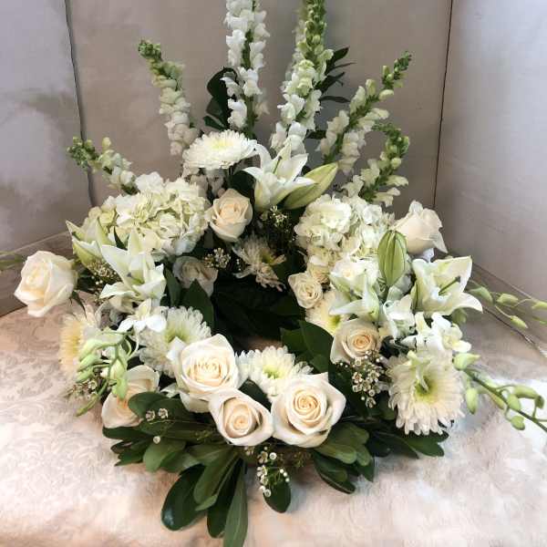 White floral arrangement with roses, lilies, and tall snapdragons