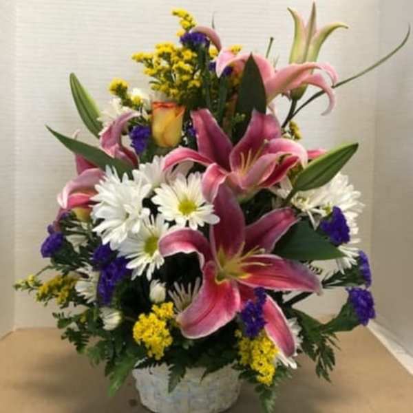Pink lilies and white daisies in a low basket arrangement