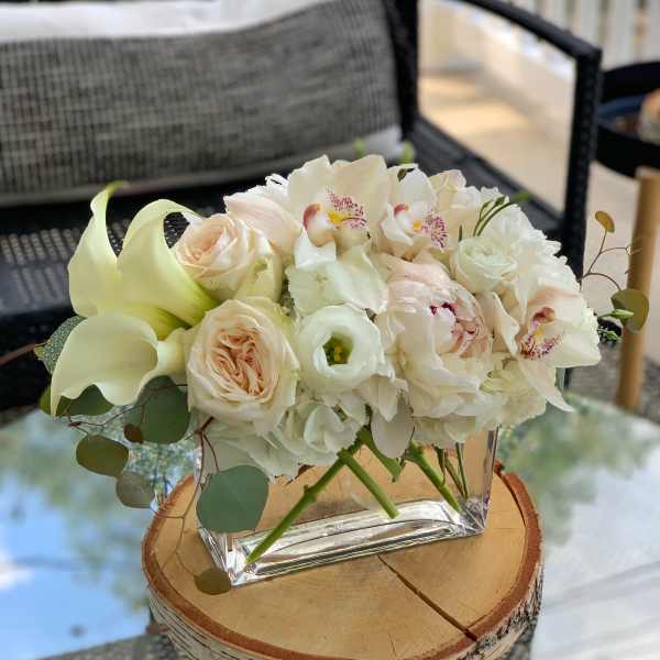 White and blush floral arrangement in a clear square vase