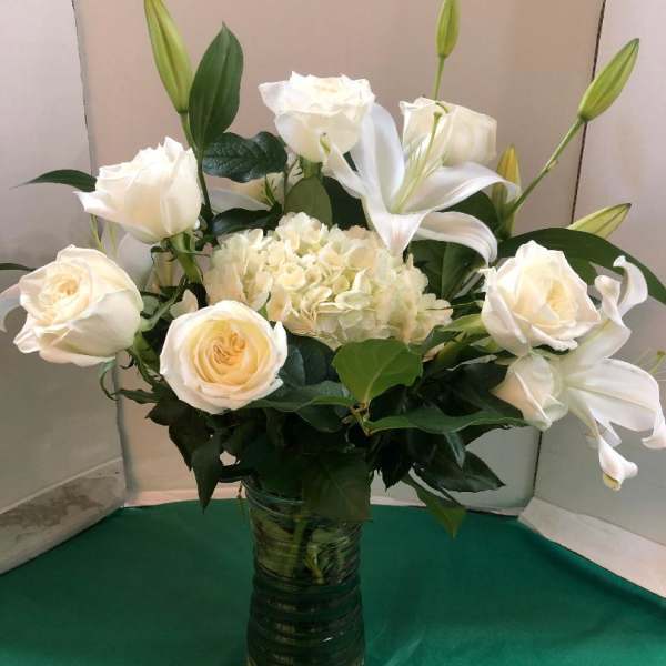 White roses and lilies arranged in a glass vase