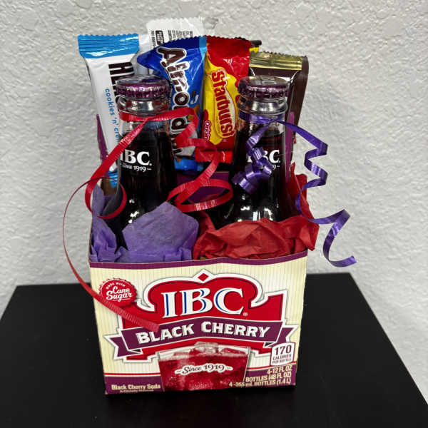 Gift basket with soda bottles and candy bars wrapped in colorful tissue and ribbons