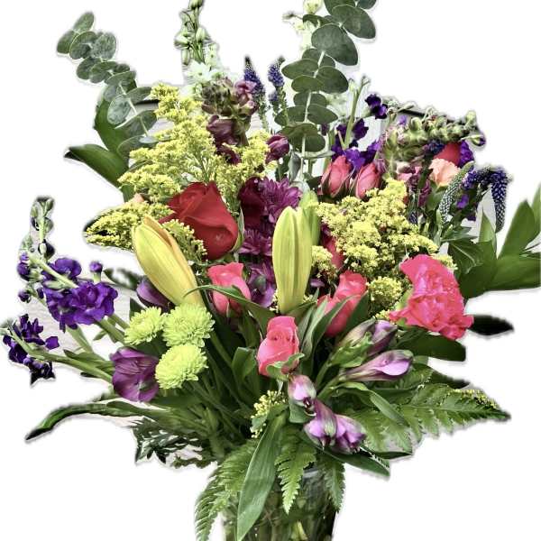 Mixed bouquet of pink, purple, yellow, and red flowers in a clear glass vase