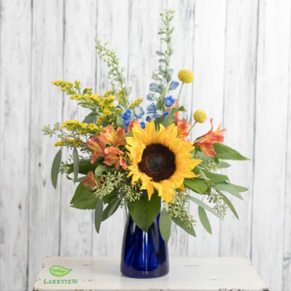 Sunflower bouquet in a blue glass vase with yellow and orange accents