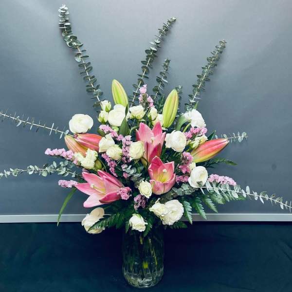 Pink and white floral arrangement with lilies and roses in a glass vase