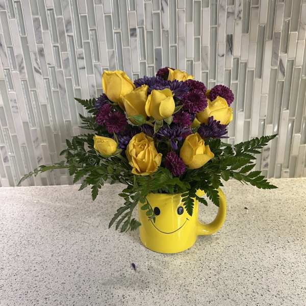 Yellow roses and purple mums in a yellow smiley-face mug