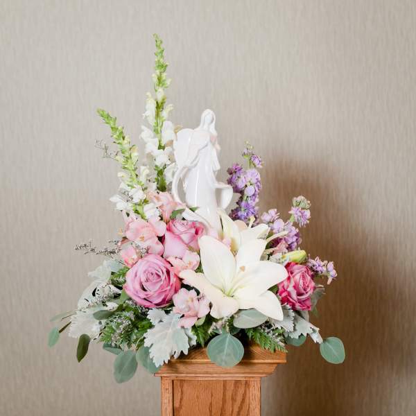 Pink and white floral arrangement with a white angel figurine