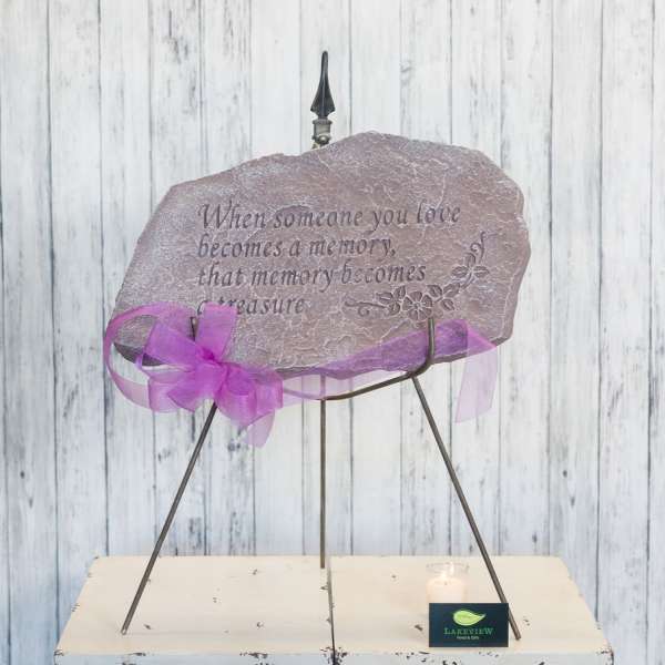 Memorial stone on a metal stand with a purple ribbon and candle