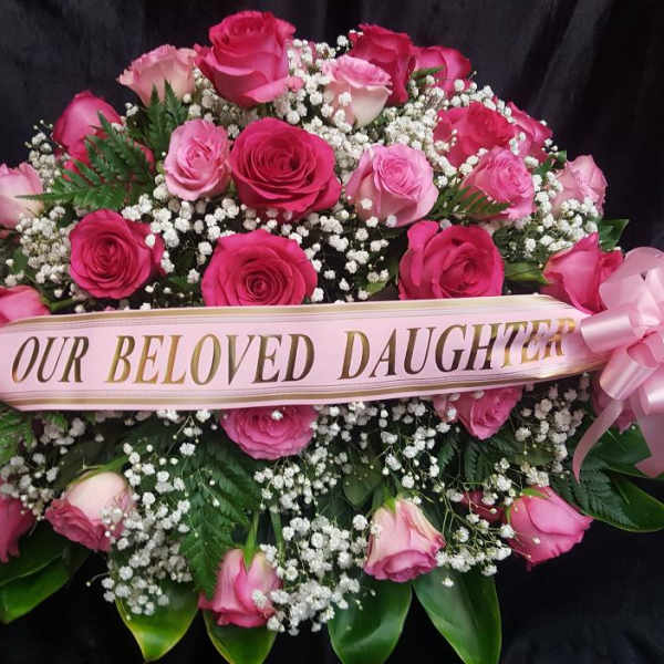 Pink rose funeral spray with a ribbon reading "Our Beloved Daughter"