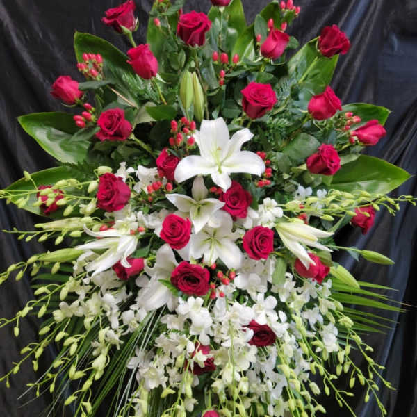 Large standing spray of red roses and white lilies on an easel