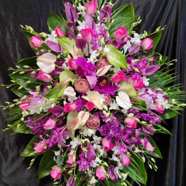 Large pink and white floral spray with tropical leaves on a black backdrop
