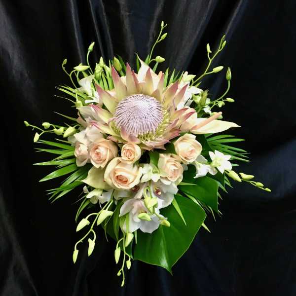 Bouquet with pale roses, white orchids, and a large protea center