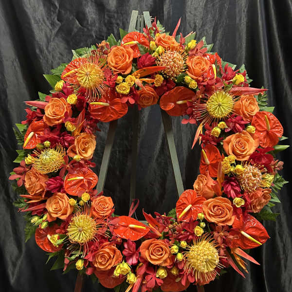 Circular floral wreath with orange and red flowers on a stand