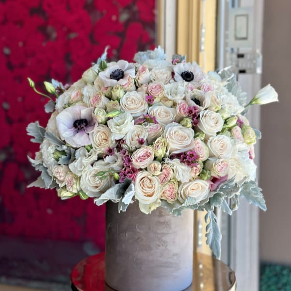 Round bouquet of white and blush roses in a gray hatbox