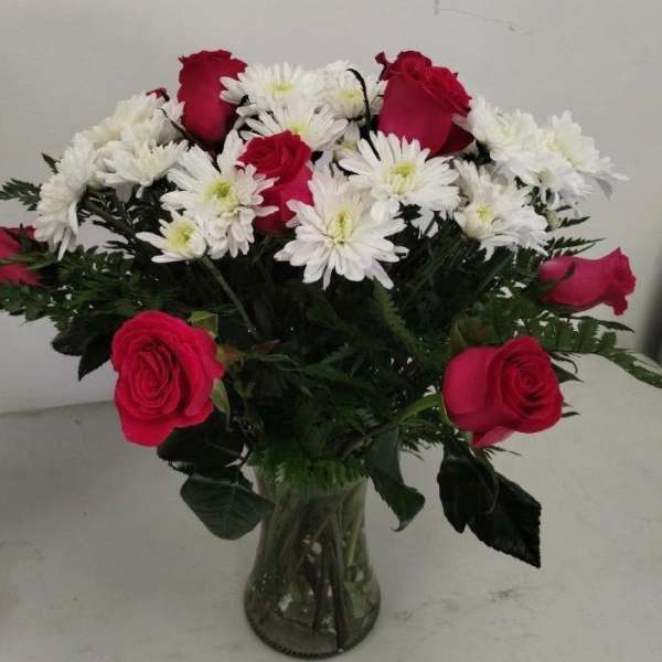 Arrangement of red roses and white chrysanthemums in a clear glass vase