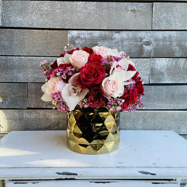 Bouquet of red and blush roses in a gold vase