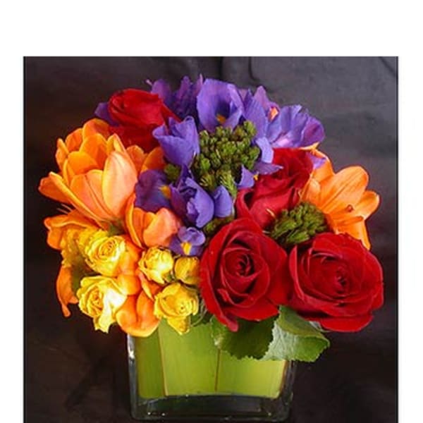 Colorful bouquet of roses, tulips, and purple flowers in a glass vase