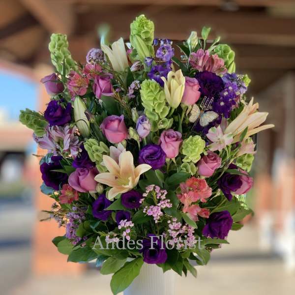 Mixed bouquet of pink, purple, and cream flowers in a white vase