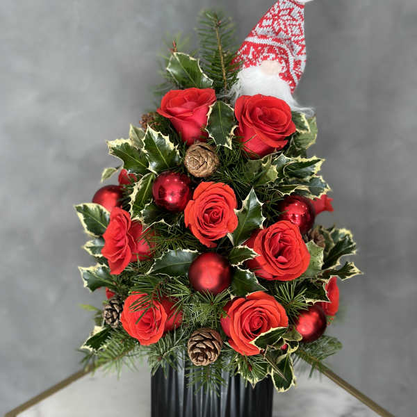 Christmas arrangement with red roses, ornaments, and a Santa hat