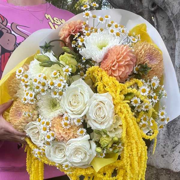 Large bouquet of white, peach, and yellow flowers with cascading yellow strands