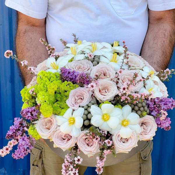 Large bouquet of pale pink roses, white flowers, and purple blossoms