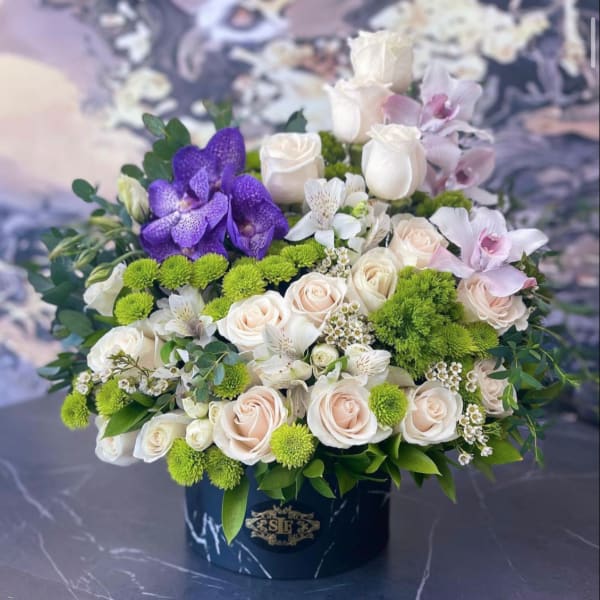 Bouquet of white and blush roses with purple orchids in a black box