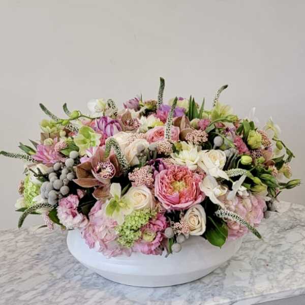 Low pastel floral arrangement in a white oval container