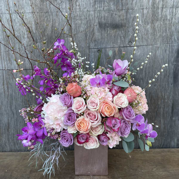 Large bouquet of pink and purple roses with orchids in a square vase