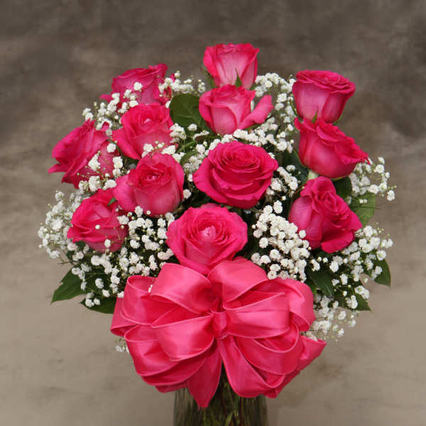Pink roses with baby's breath in a glass vase and pink bow