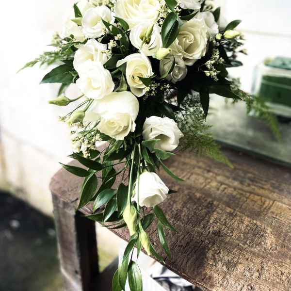 White rose bouquet with greenery on a wooden table