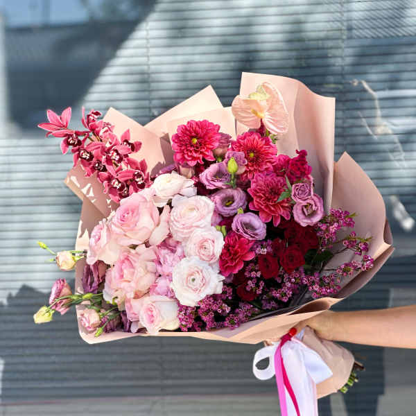 Large pink bouquet with roses, dahlias, and orchids wrapped in blush paper