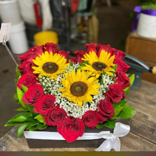 Heart-shaped bouquet of red roses and yellow sunflowers in a box