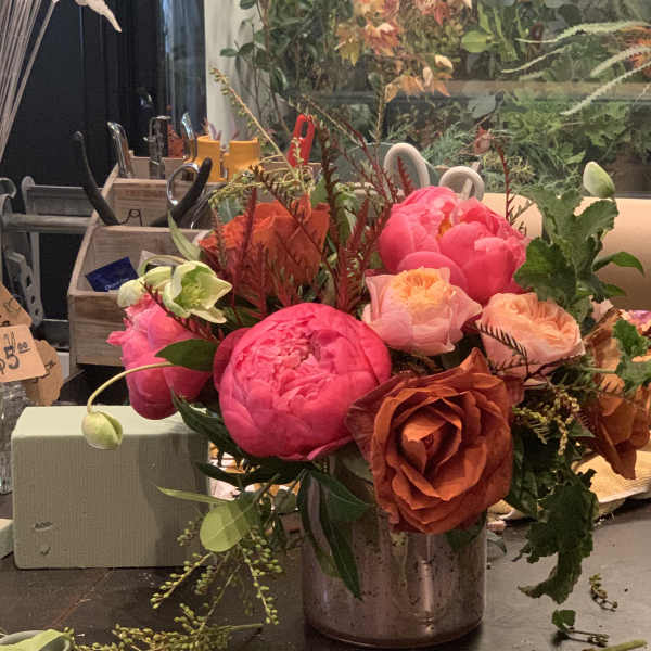 Bright pink and peach peonies and roses in a metal vase