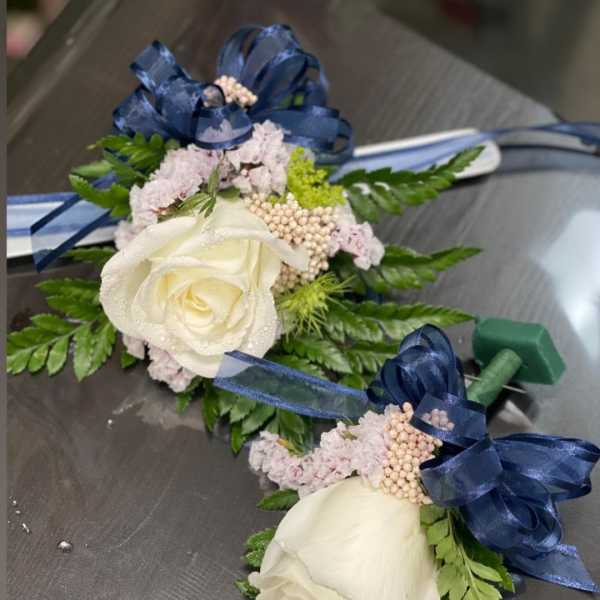 Two white rose boutonnieres with blue ribbon bows