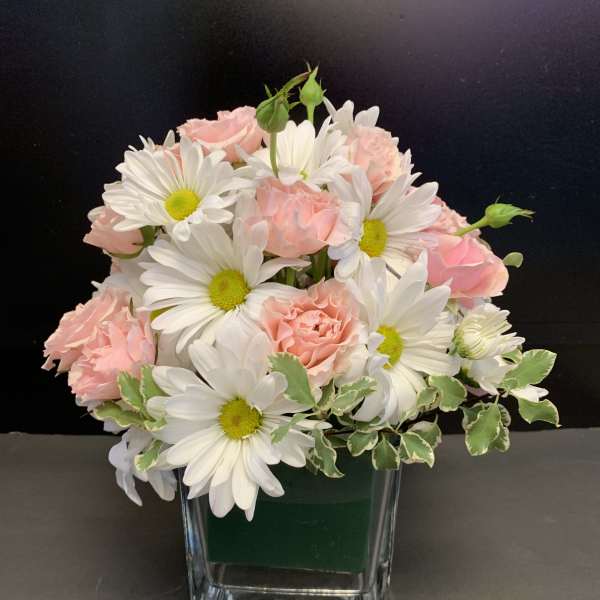 Pink roses and white daisies arranged in a clear glass vase